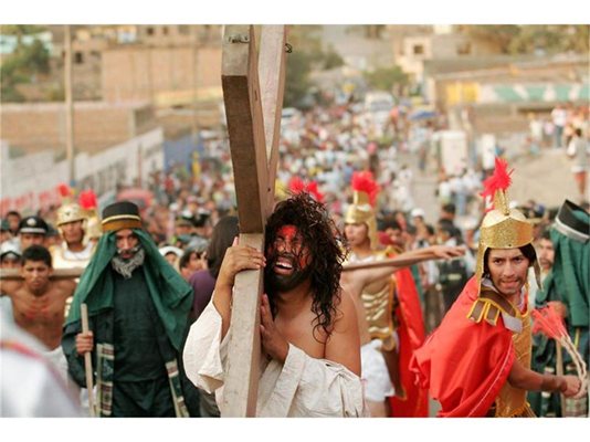 Мъж, облечен като Исус Христос, носи кръста по време на шествие в Лима.