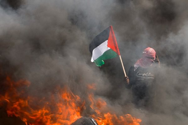 Мъж държи палестинско знаме до горящи гуми по време на протест срещу израелско-палестинската среща в Шарм ел-Шейх.
СНИМКА: РОЙТЕРС