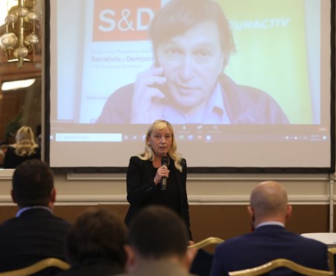 Елена Йончева открива дискусията в София.
На видеостената зад нея е Георги Готев, който водеше събитието от Брюксел.