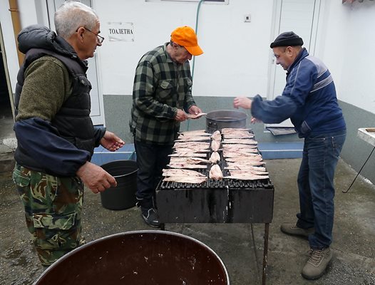 В двора на храма на скара с дървени въглища пекат скумрия за курбан.