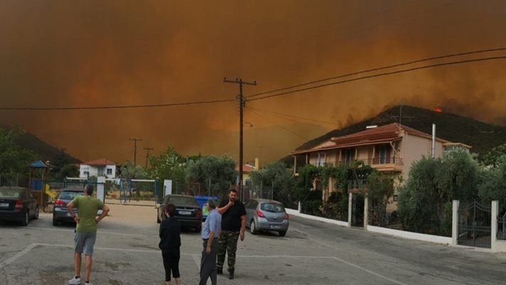 Жители на Тасос гледат огненото зарево и дима.