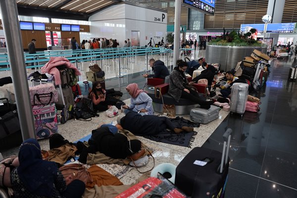 Пътници спят на летището в Истанбул, след като полетите им бяха отменени заради лошото време.