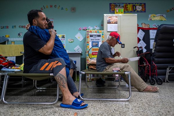 Мъж прегръща малко момиче. Те са се евакуирали в училище в Пуерто Рико заради урагана "Фиона"