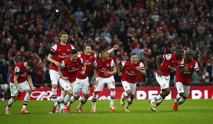 Играчите на “Арсенал” тръгват да се радват след решителната дузпа срещу “Уигън”, вкарана от Санти Касорла.