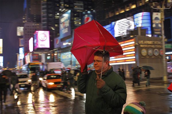 Жител на Ню Йорк опитва да се предпази от дъжда. 