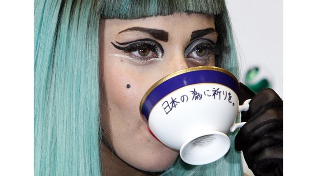 Певицата пие чай от чаша, на която пише “Молете се за Япония”. Тя участва в благотворителен концерт за жертвите на труса от 2011 г.