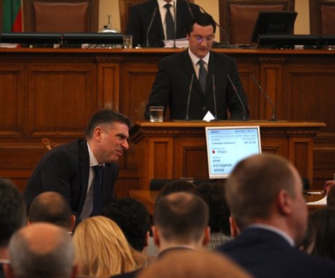 Шефът на правната комисия Данаил Кирилов разговаря с колеги в пленарната зала, докато соцдепутатът Крум Зарков се изказва от трибуната.  СНИМКА: НИКОЛАЙ ЛИТОВ