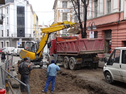 Багер изгребва калта и я товари в камион.