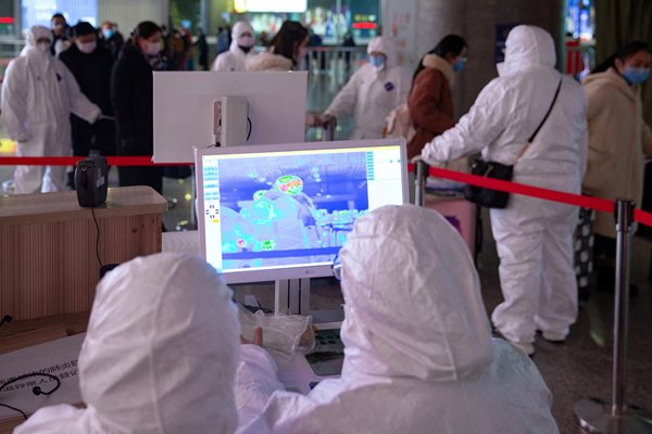 Служители сканират температурата на пътниците, пристигащи на гарата в китайския град  Нанцзин, за да  търсят заразени с коронавируса.