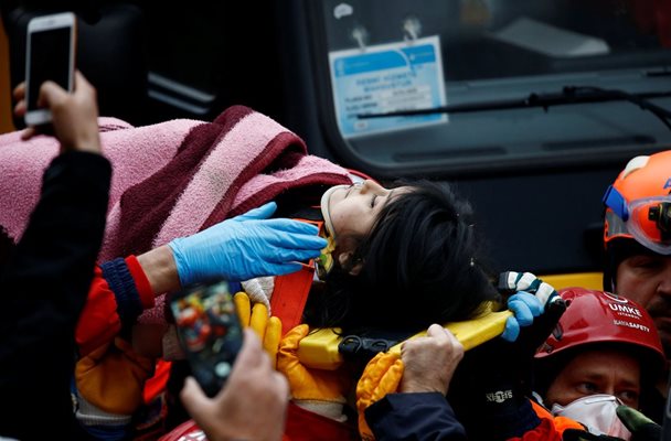 Спасителите отнасят спасено от под руините момиче Снимка: Ройтерс