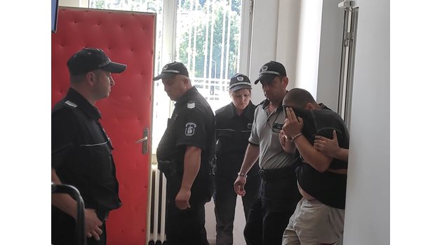 Водят Делян Бешев в съда в Габрово, а той крие лицето си.
