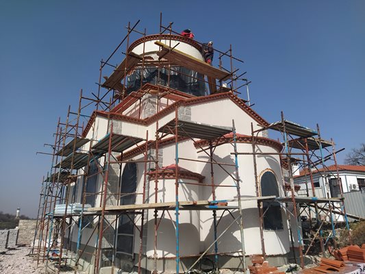 Работници поставят керемиди по купола на новия храм.