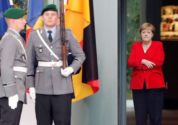 Ангела Меркел си държи ръцете скръстени на среща, за да не се вижда, че трепери.