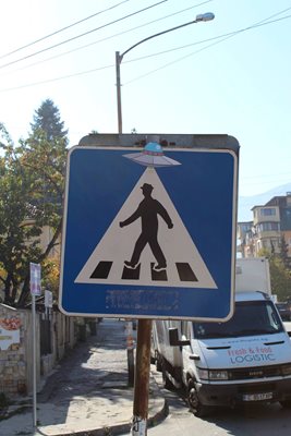 Първият пътен знак, който претворява уличният артист, е на пешеходец с НЛО.