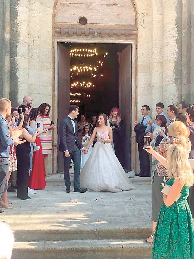 Синът на Петя Буюклиева с булката си приемат овациите на гостите си след венчавката.
