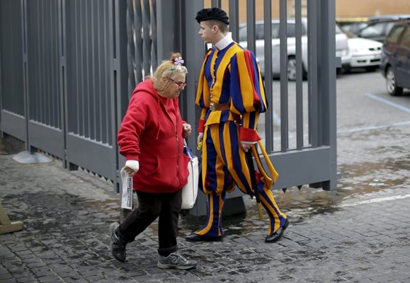 Бездомна жена минава покрай гвардеец във Ватикана.