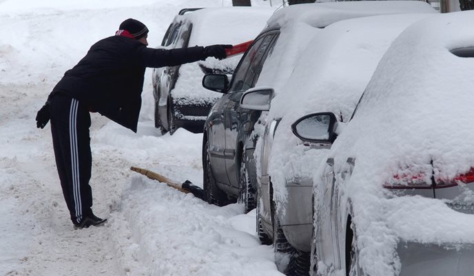 Мъж разчиства колата си, затрупана от сняг. СНИМКА: Pixabay