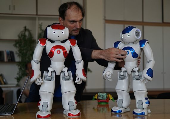 Учен от Института по роботика показва роботите Роби и Роберта.