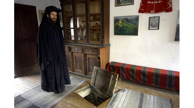 Отец Нектарий от Гложенския манастир показва дупката, в която се е криел Левски.