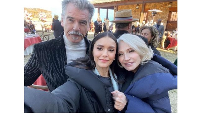 Nina Dobrev on the set, hugged by Pierce Brosnan