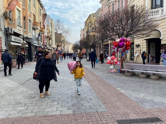 Детенце носи балон с формата на сърце.