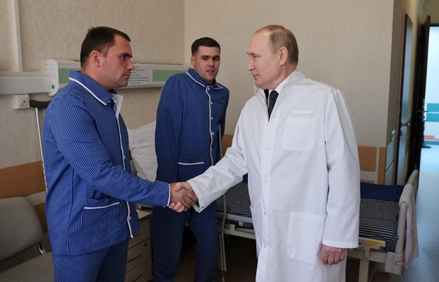 Путин, облечен с бяла престилка, разговаря с войнците в една от московските военни болници. СНИМКА: РОЙТЕРС