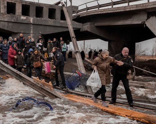Цивилни пресичат разрушен мост - единствения път за бягство от бомбардирания град Ирпин, разположен на около 25 км от Киев.