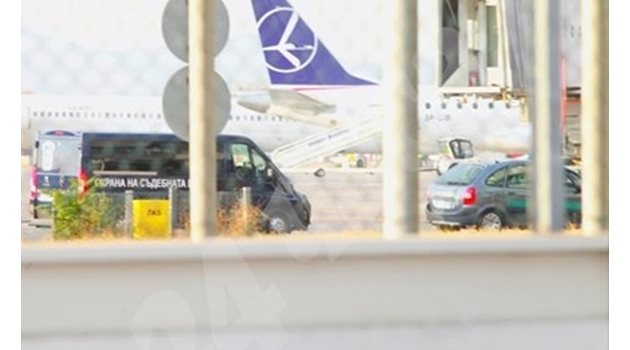 Кола на съдебна охрана чака кацането на самолета, в който пътува Северин