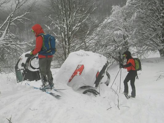 Спасители на ски стоят край колите на туристите, които са потънали в преспите.