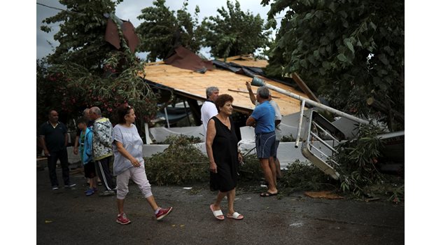 Туристи оглеждат щетите след бурята в Гърция.
