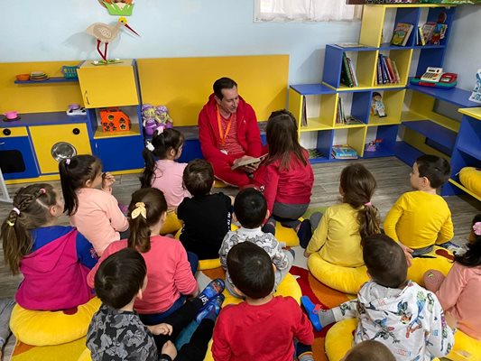 Деца слушат в захлас, докато Георги Мараджиев им чете приказки.