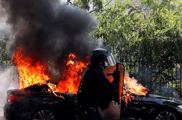 Френски полицейски служител преминава покрай горящ автомобил по време на демонстрацията на "жълтите жилетки" в Париж