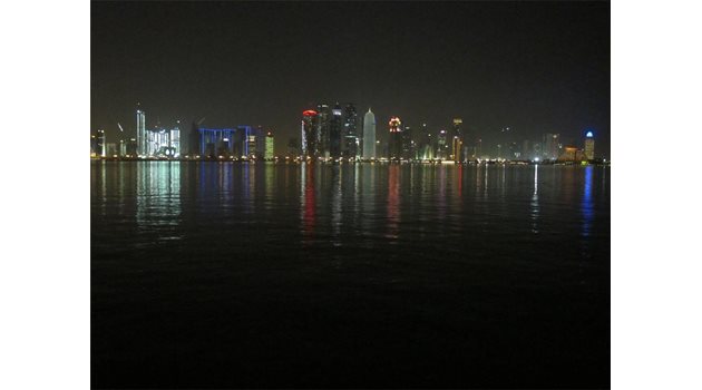 Нощната красота на крайбрежието с небостъргачите в Доха