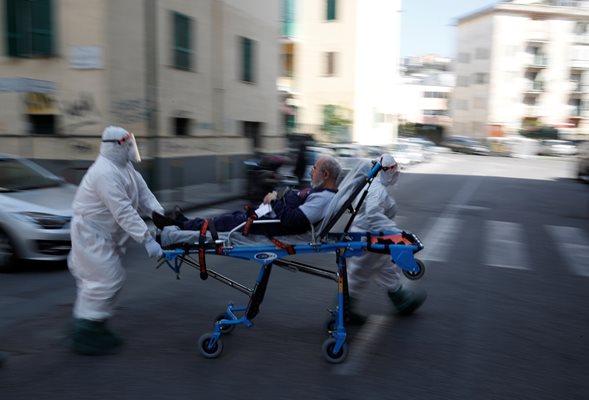 Лекари в пълна защитна екипировка карат пациент към болница в Неапол.