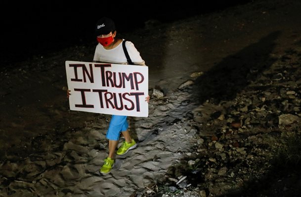 Привърженик на бившия президент на САЩ държи плакат с надпис “Вярвам в Тръмп”.