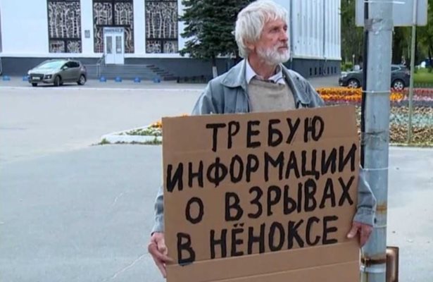 Възрастен мъж държи плакат, с който иска информация за инцидента на полигона край село Ньонокса.