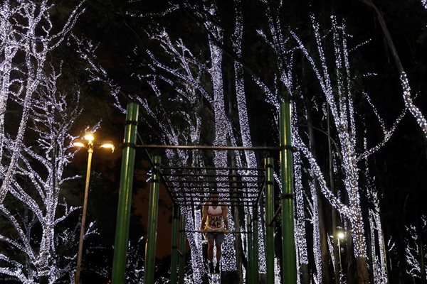 Мъж тренира сред дървета с коледни лампички в Сао Пауло, Бразилия