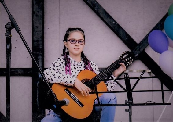 Ученичката свири на китара по време на концерт.

