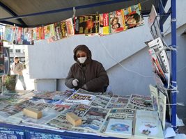 В Плевен жена с маска и ръкавици продава вестници.

