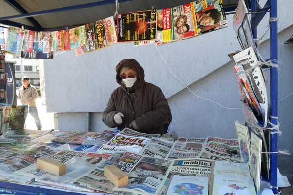 В Плевен жена с маска и ръкавици продава вестници.

