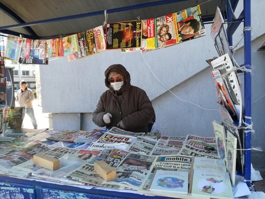 В Плевен жена с маска и ръкавици продава вестници.

