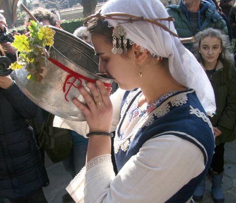 Девойка в народна носия опитва от виното