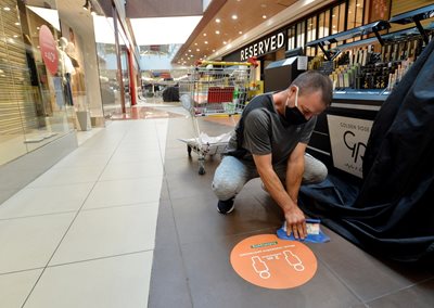 An employee places distance markers in a shopping center in Sofia.  PHOTO: YORDAN SIMEONOV