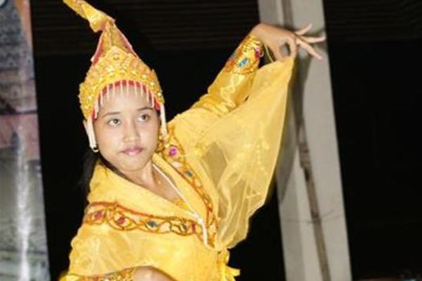 Момиче, облечено в традиционни дрехи, танцува на празненство.