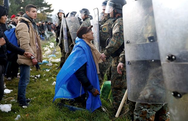 Бежанец е коленичил пред униформените на границата.