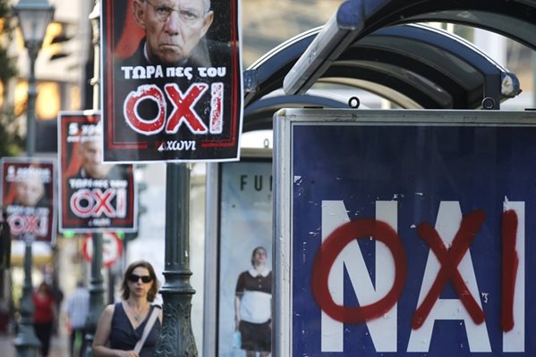 Жена върви по улица в Атина, изпъстрена с плакати на германския финансов министър Волфганг Шойбле, под който е написано "не" на гръцки.