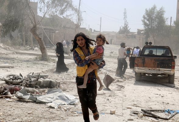 Мъж тича с ранено момиченце в ръце, за да се спаси от въздушните удари върху предградие на Алепо. Всеки ден там измират цивилни, сред които и много деца.