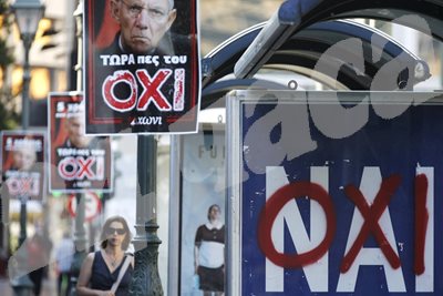 Жена върви по улица в Атина, изпъстрена с плакати на германския финансов министър Волфганг Шойбле, под който е написано "не" на гръцки.