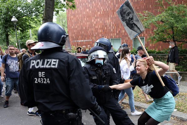 Полицаи задържат момиче по време на протест срещу правителствените мерки за ограничаване на COVID-19 в Берлин.

