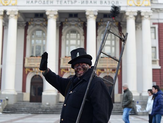 Дегизиран коминочистач отправя пожелания за новата година на минувачи пред Народния театър.
СНИМКА: ЙОРДАН СИМЕОНОВ